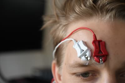 An image of a testing person using a fEMG measurement device placed to his forehead that records facial muscle movement