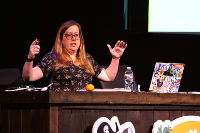 Katie Sylor-Miller at a desk on stage with a laptop