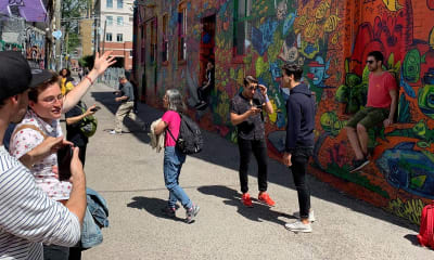 People in a street taking photos of graffiti
