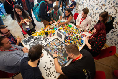 Overhead shot of people doing jigsaw puzzles and building lego