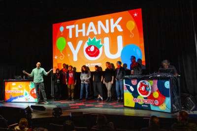 A lineup on stage in front of a screen saying Thank you
